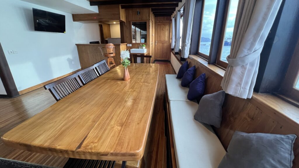 Wooden dining table with cushioned bench seating in the passenger lounge