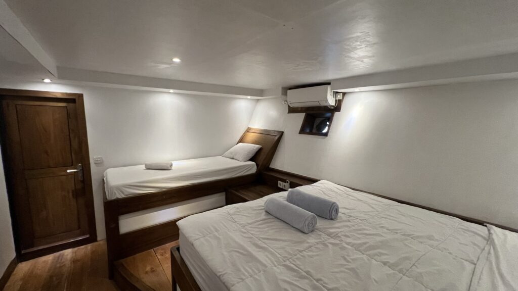 Twin bed positioned beside a double bed in a shared cabin layout