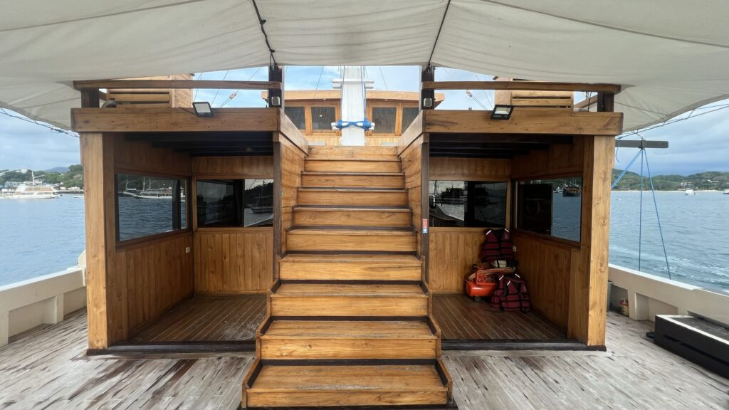 Wooden staircase to the upper deck between two shaded lounge areas