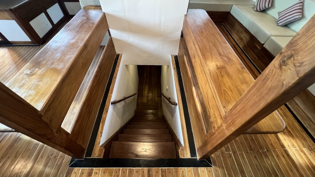 View down a wooden interior staircase to the lower deck cabins