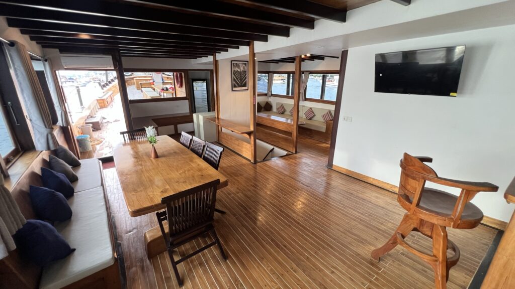 Panrita's main salon with dining table, wall-mounted TV, and polished wood flooring