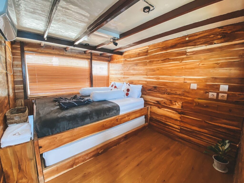 Deluxe Cabin with wood-paneled walls, slatted blinds and a neatly made bed