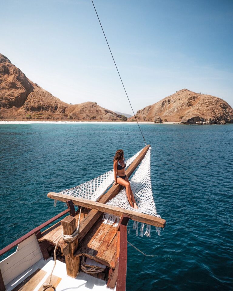 Guest sitting on Papiton Duwa's bow net looking toward Komodo's hills