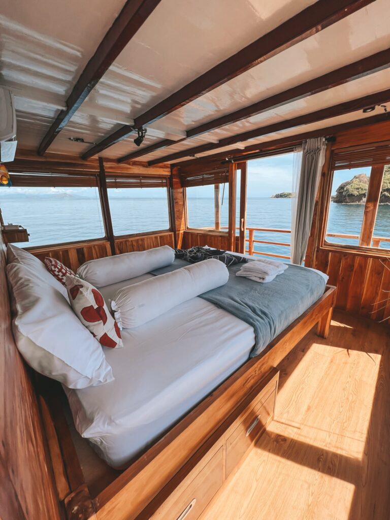 Bed in Papiton Duwa's Master Cabin with wraparound windows overlooking the hills