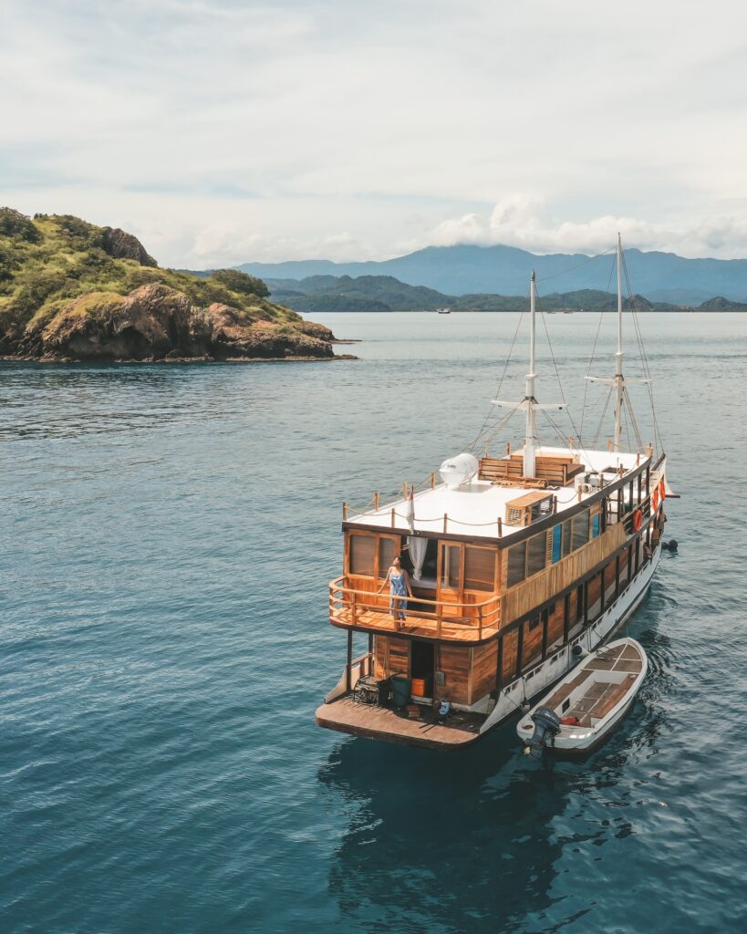 Aerial view of Papiton Duwa's stern with a tender boat moored alongside in a calm bay