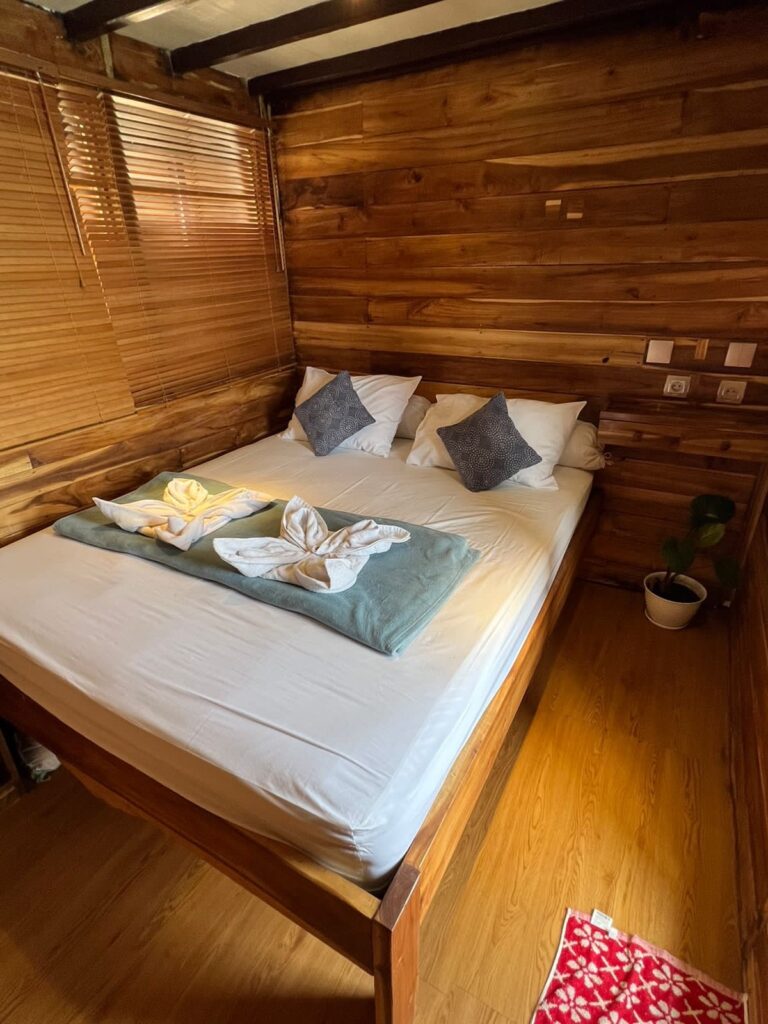A wood-paneled cabin bed with patterned pillows and a small potted plant