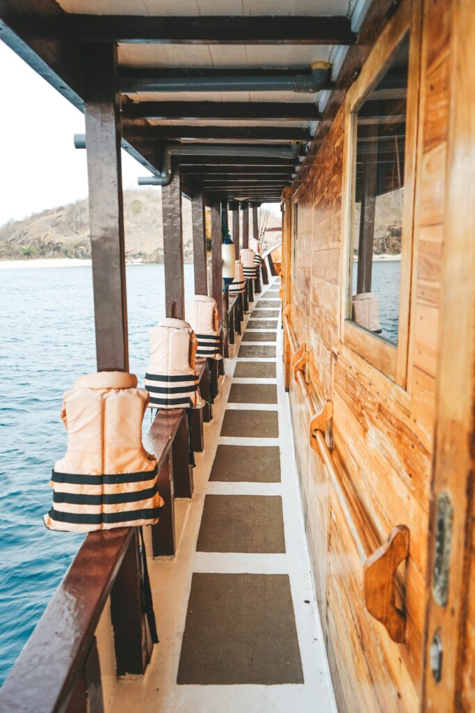 Life vests lined along a wood-paneled side deck walkway overlooking the sea