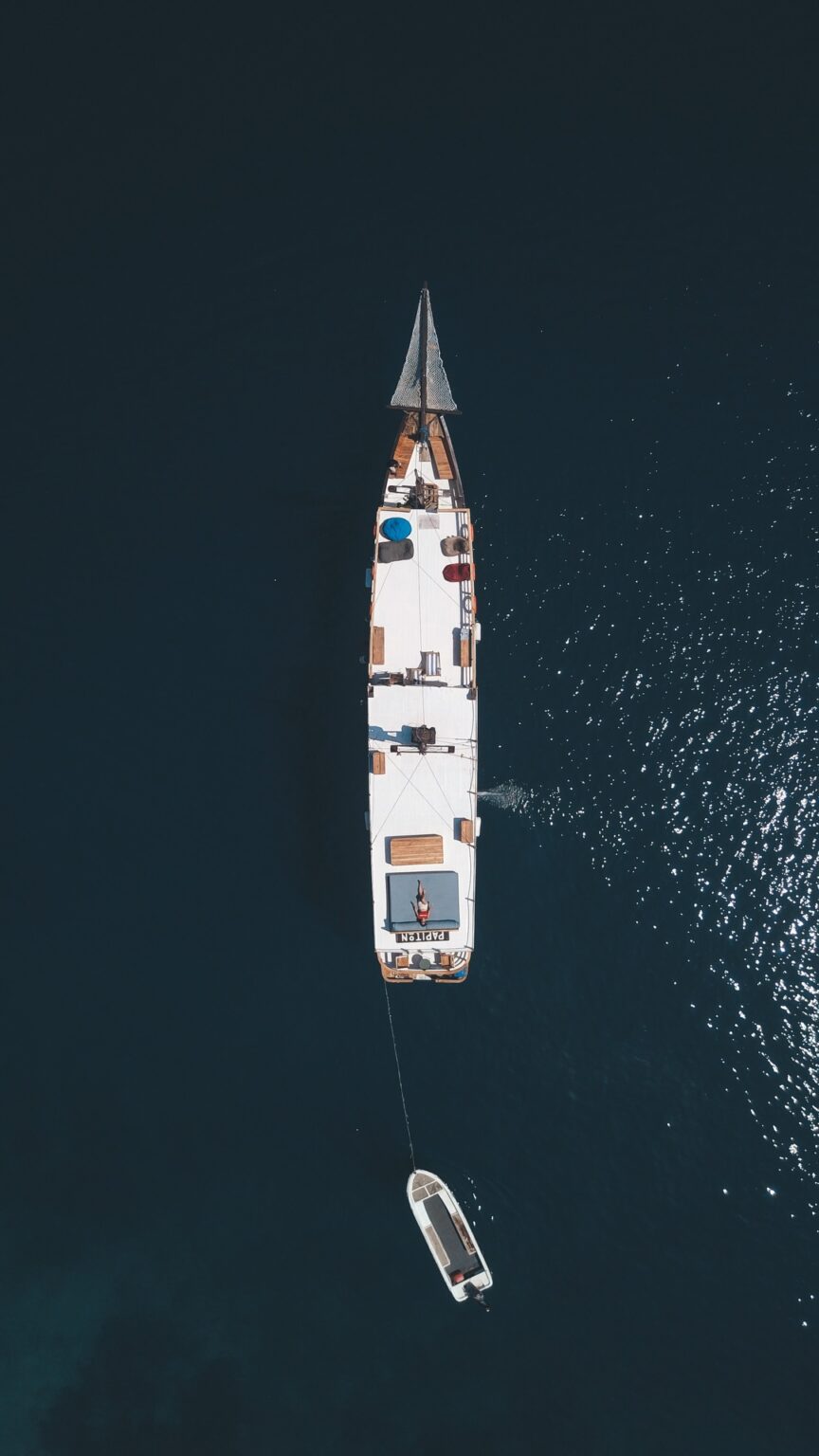 Papiton Lopi liveaboard seen directly overhead anchored in deep blue water with its tender