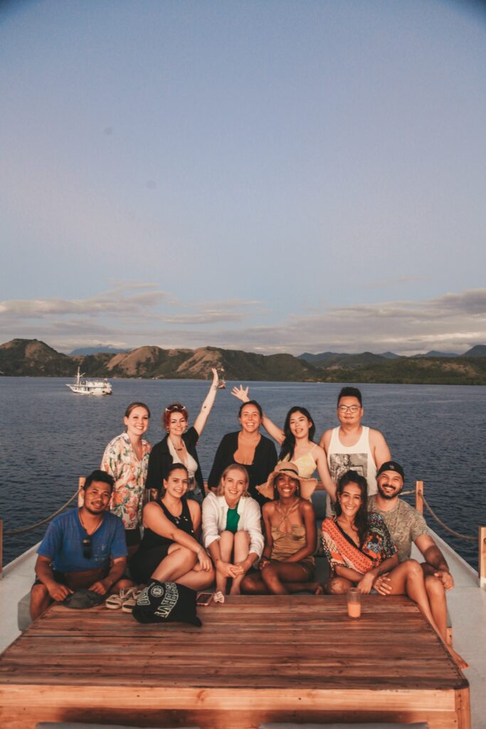 A group of travelers pose on Papiton Lopi's stern deck at golden hour
