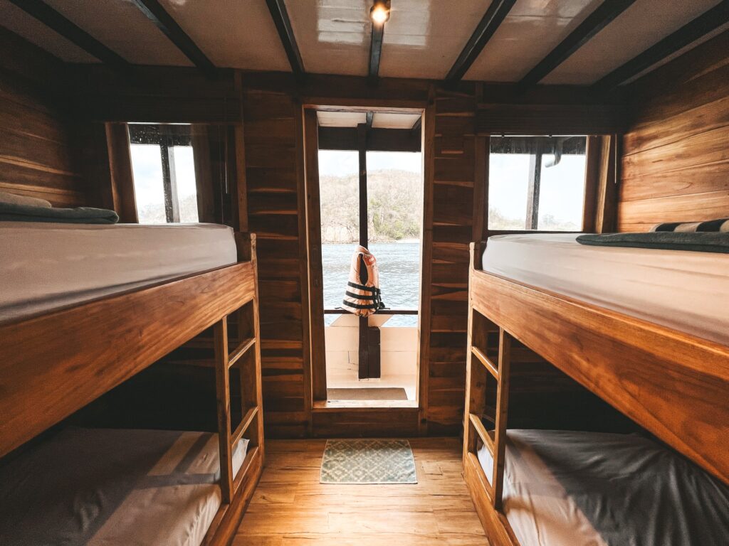 Bunk beds line both walls of a cabin leading to an open deck door with ocean views