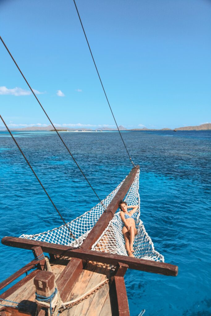 A guest relaxes in Papiton Lopi's bowsprit net above clear blue water