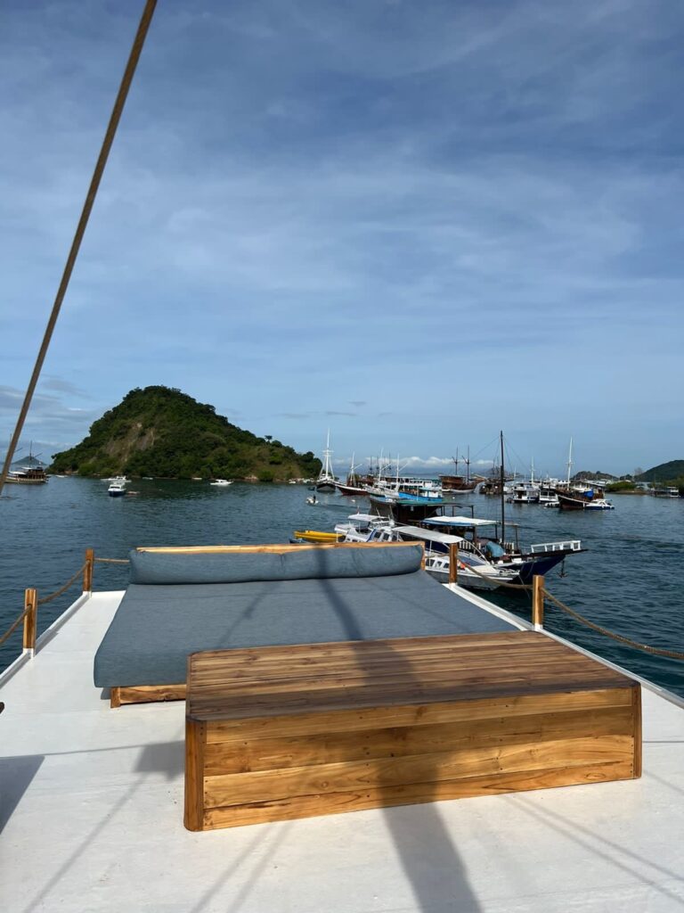 A wooden bench and sun pad on Papiton Lopi's top deck overlooking a busy harbor