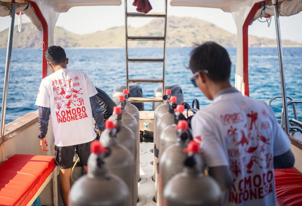 Scuba tanks lined up on deck with crew preparing gear before a dive