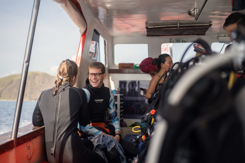 Guests in wetsuits chatting inside the shaded cabin of Red Whale during transit