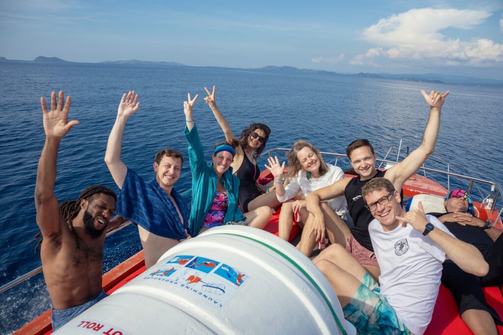Group of guests waving and smiling on the speedboat's bow during a sunny trip