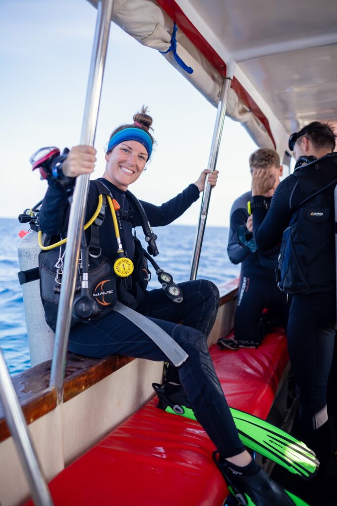 Diver smiling while preparing gear seated on the speedboat's cushioned bench