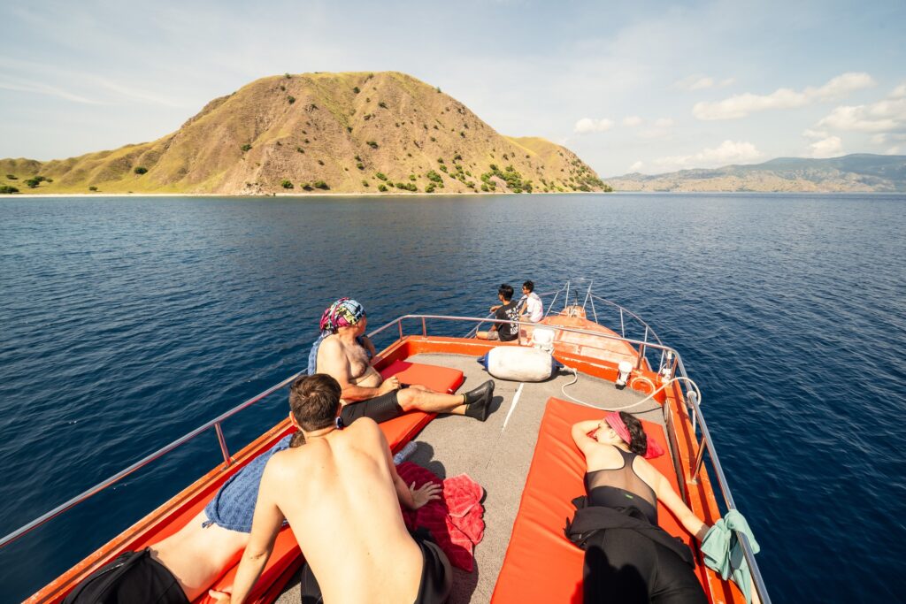 Guests sunbathing on the bow of Red Whale as it cruises past coastal hills