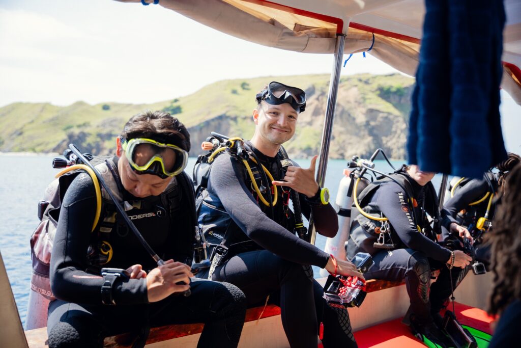 Divers in wetsuits and gear seated on the Red Whale Komodo speedboat before a dive