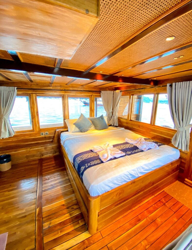 Deluxe cabin with panoramic sea-view windows and blue accent pillows on the bed