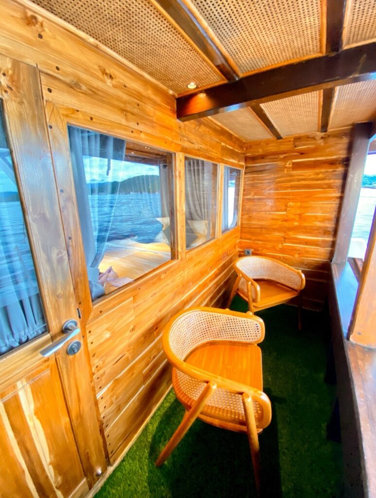 Private balcony with two wicker chairs and artificial turf flooring outside a cabin