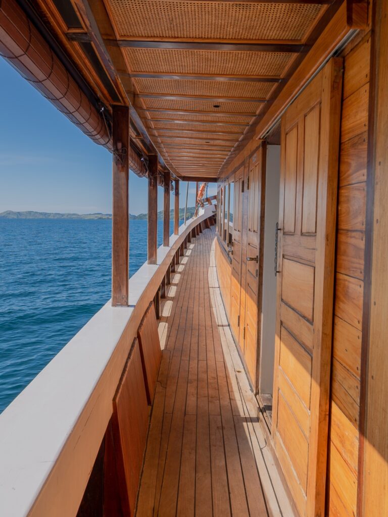 Refviero komodo liveaboard side deck walkway with polished teak flooring and wooden doors