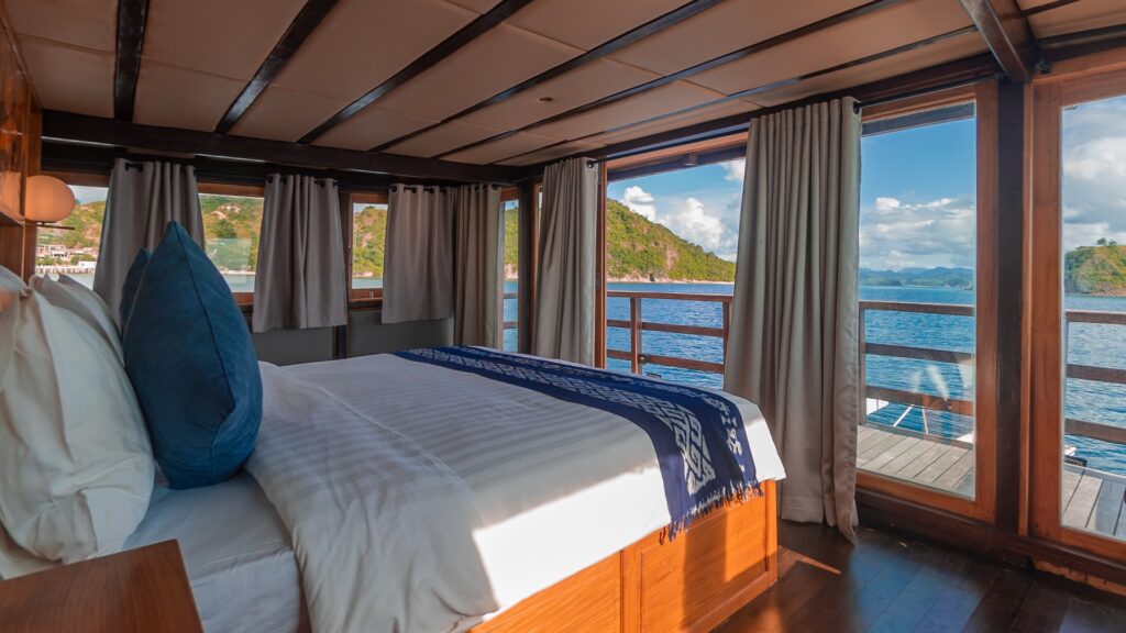 View from the bed through wide windows overlooking the sea and green islands