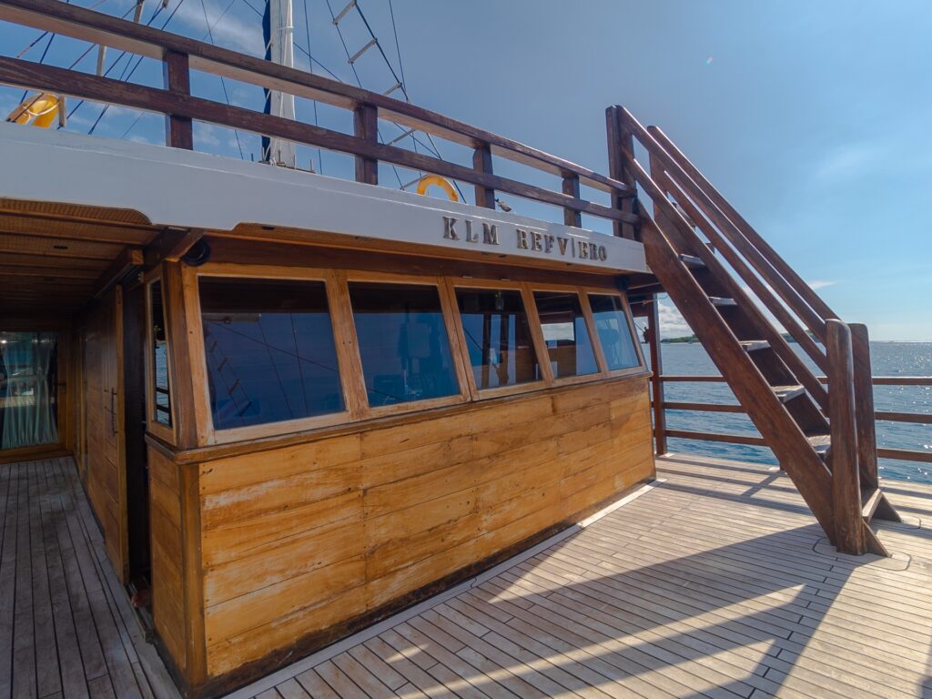 Wooden upper deck cabin wall with painted signage and stairway leading to the bridge