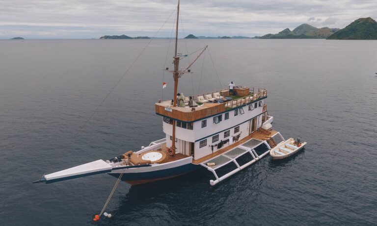 Sea Familia Komodo liveaboard aerial view showing traditional phinisi profile and support boats