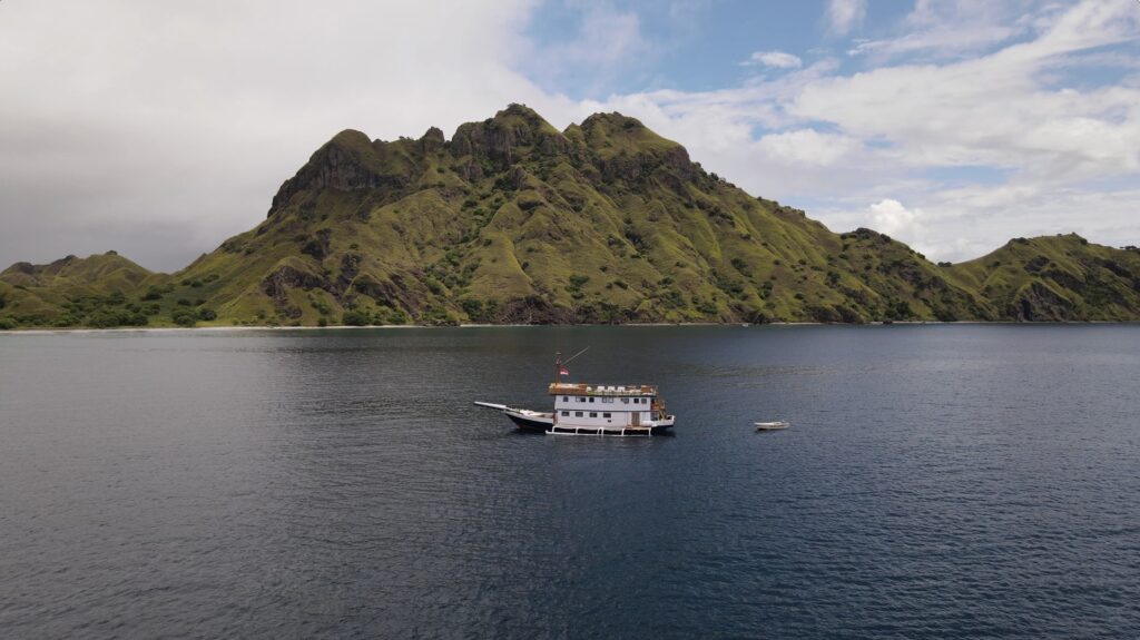 Sea Familia anchored below tall green hills near Padar Island