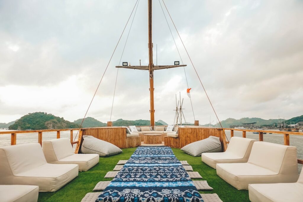 Sea Familia's top deck lounge with turf flooring, white loungers, and blue ikat mats