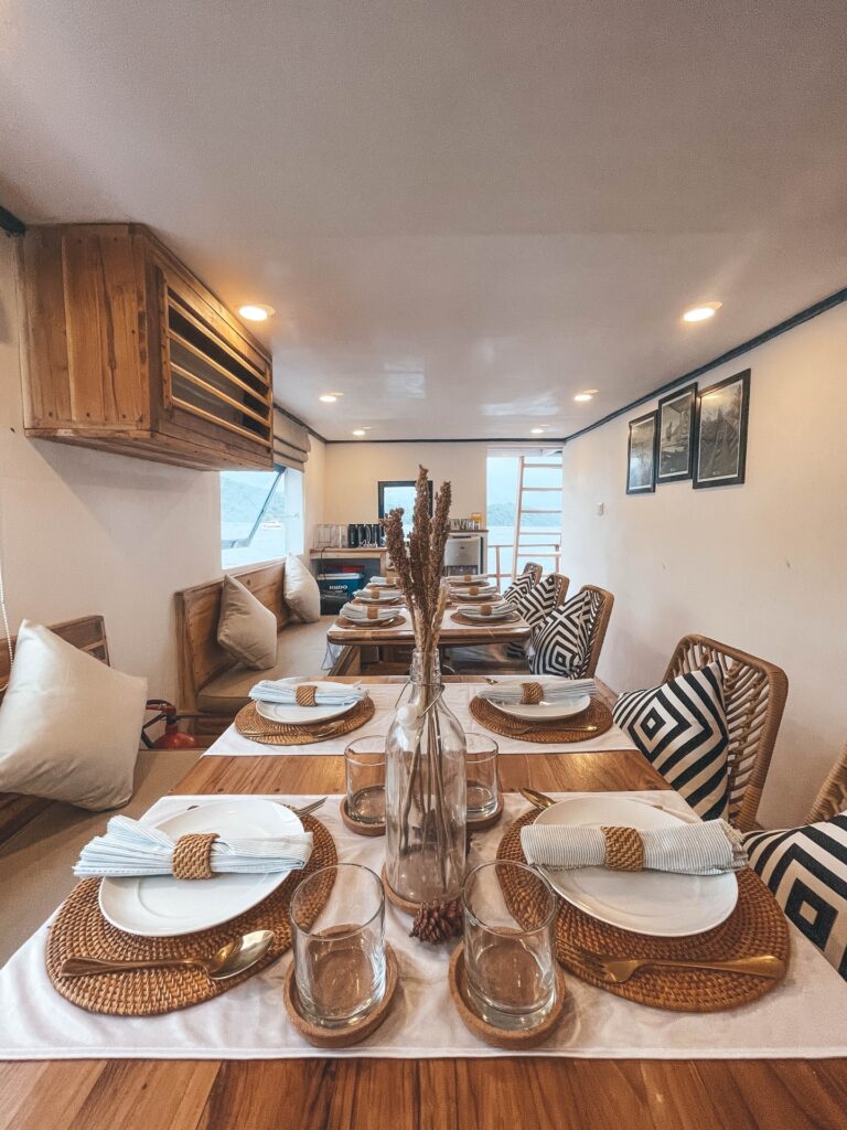 Wide view of the dining table with glass bottle centerpieces and patterned cushions