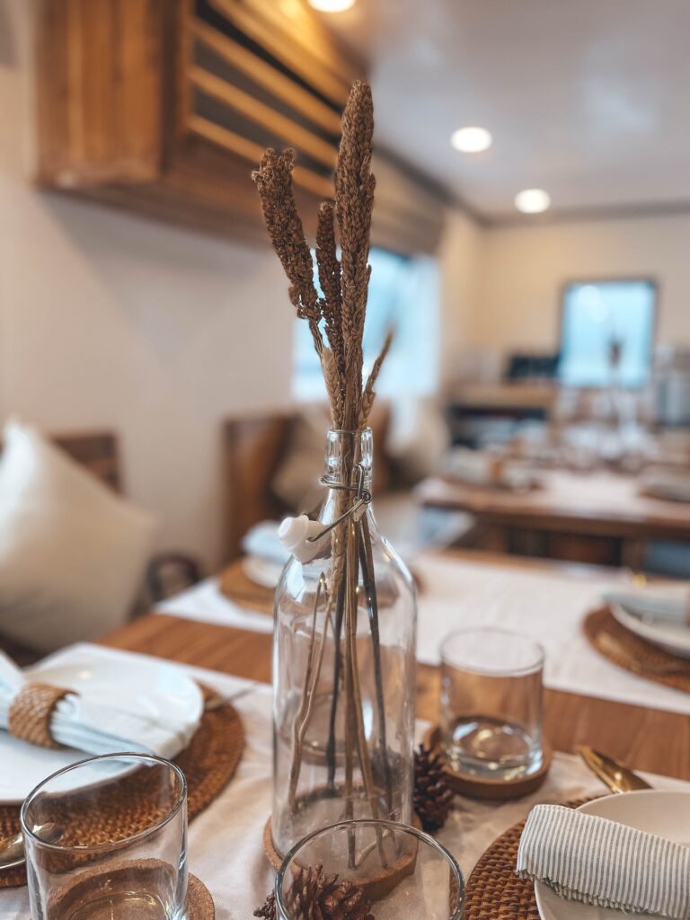 Glass bottle with dried wheat stalks as a centerpiece on the dining table