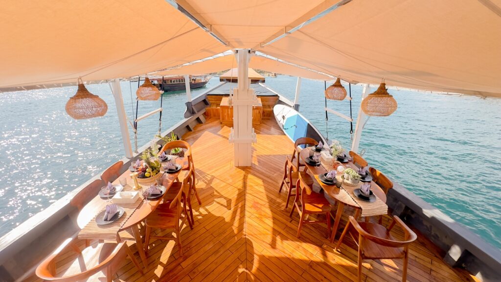 Semesta Voyage's covered dining deck with two long tables set under a canvas awning