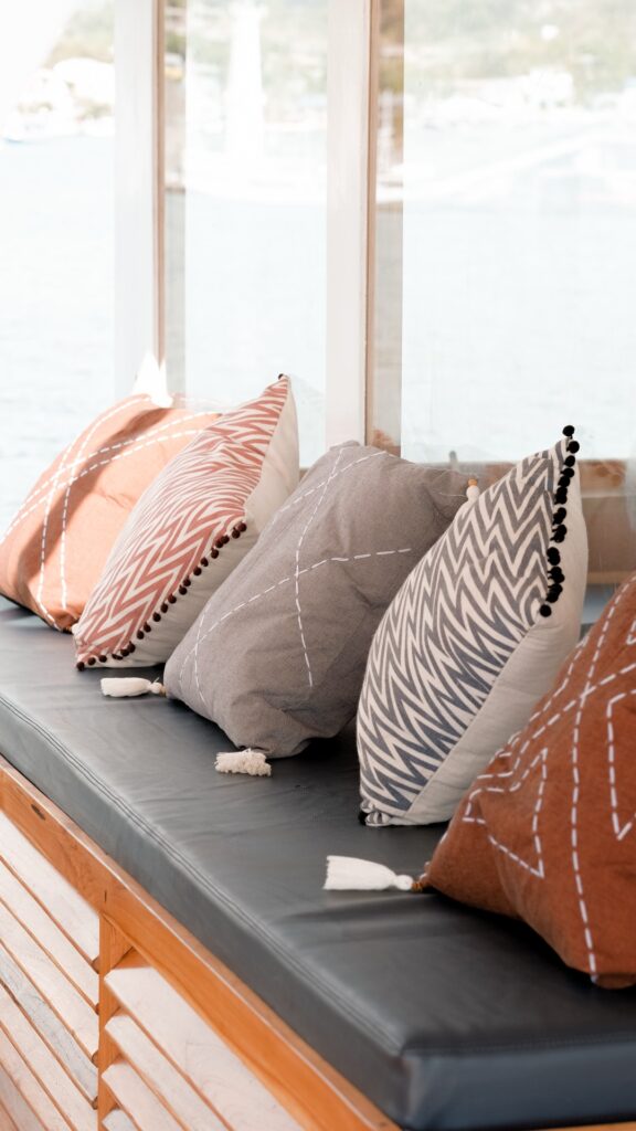 Terracotta and grey patterned cushions arranged along a wooden window bench
