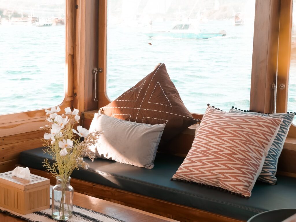 Semesta Voyage's indoor lounge with grey cushions and a large window over the sea