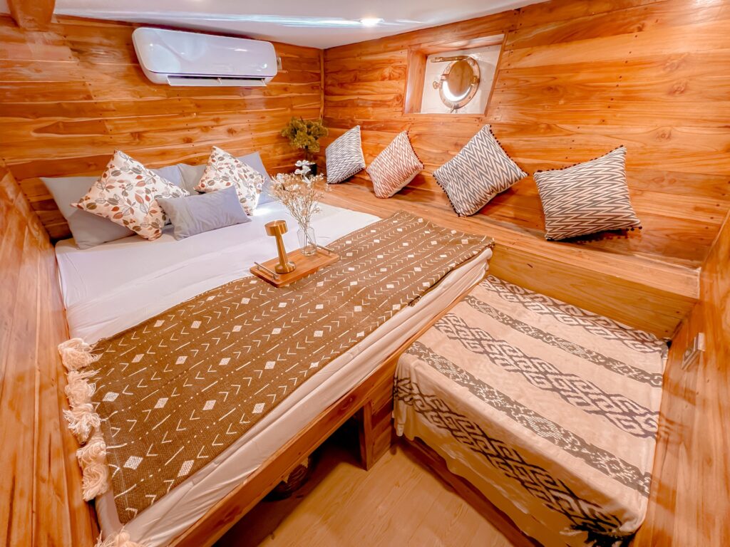 Venus cabin with twin wood-framed beds, patterned cushions, and a round porthole window