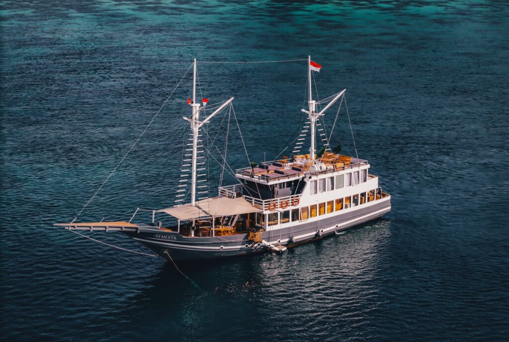 Aerial view of the Semesta Voyage Komodo liveaboard phinisi with twin masts and open sun deck