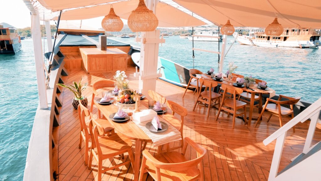 Semesta Voyage's shaded main deck lounge with wicker pendant lights and harbor views