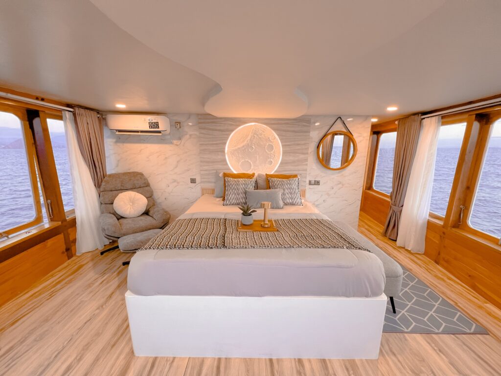 Moon Suite bedroom with a king bed, round backlit motif, and wraparound sea-view windows