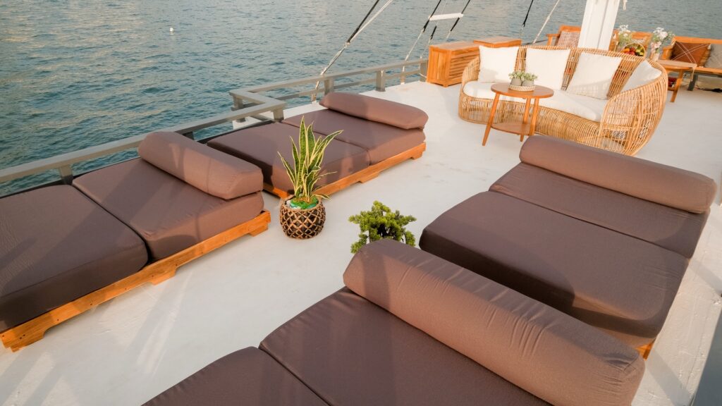Sky deck sun loungers in brown cushions beside a curved wicker lounge chair