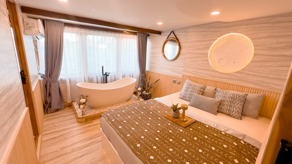 Sun Suite bedroom with a patterned bed throw, freestanding tub, and round wall mirror