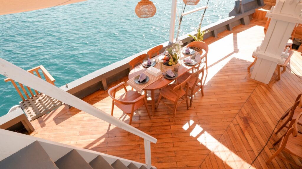 Wooden outdoor dining table set for breakfast on the Semesta Voyage's deck, seen from above