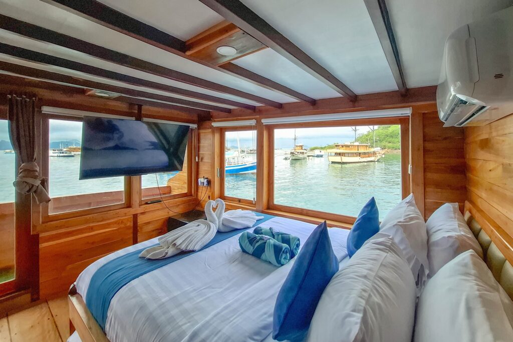 Master Suite bed with blue linens and a wall-mounted TV facing the harbor
