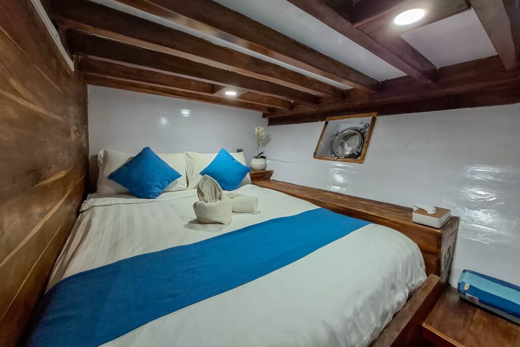 Soe Besar Vanrei's Superior cabin with wooden beams and a round porthole window