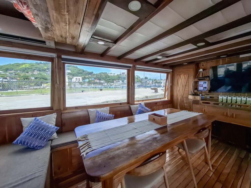 Indoor salon dining table with blue pillows and a harbor view through large windows