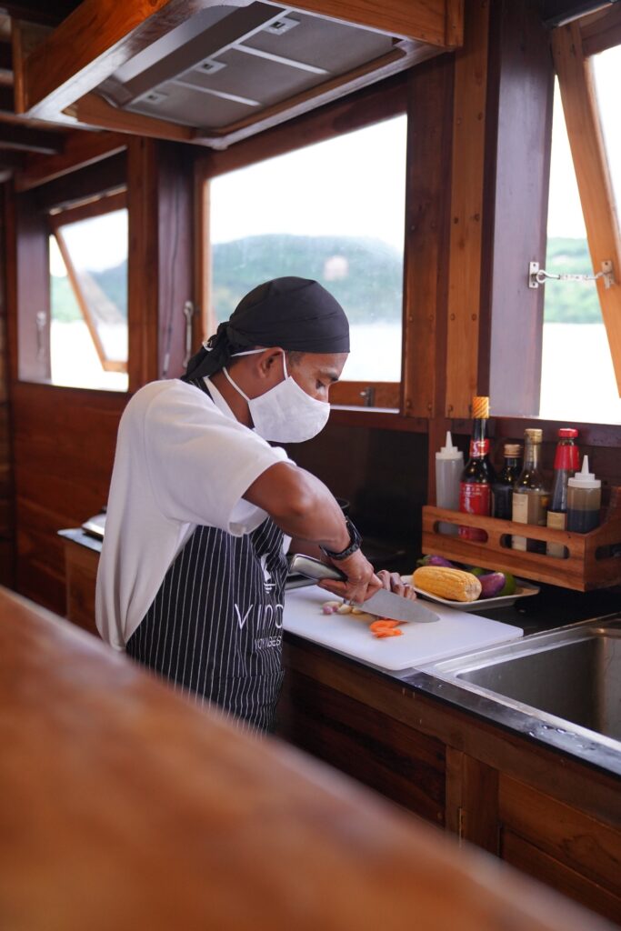 Onboard chef in a mask preparing fresh vegetables in the galley