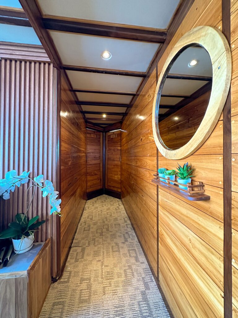 Wood-paneled hallway with a round mirror and potted orchids on display