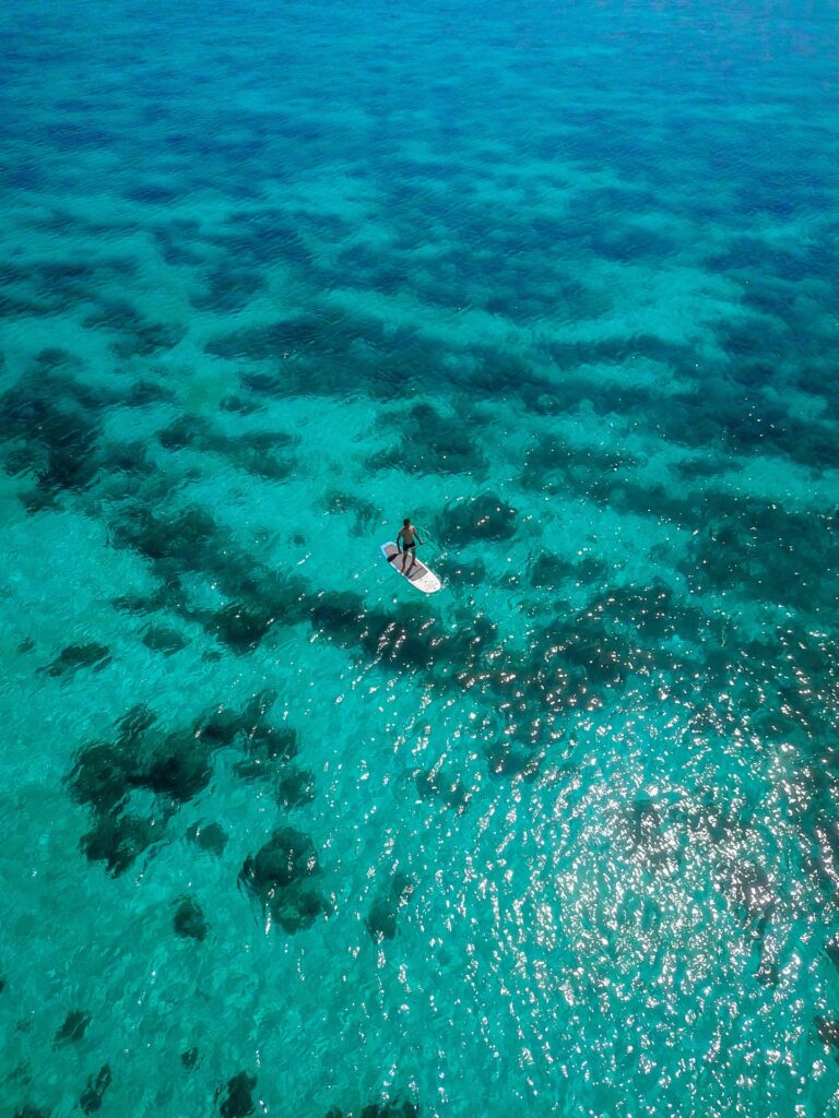Aerial view of a stand-up paddleboarder alone in open turquoise water