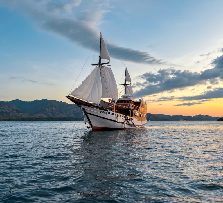 Vinca Voyage Komodo liveaboard phinisi under full sail at sunset
