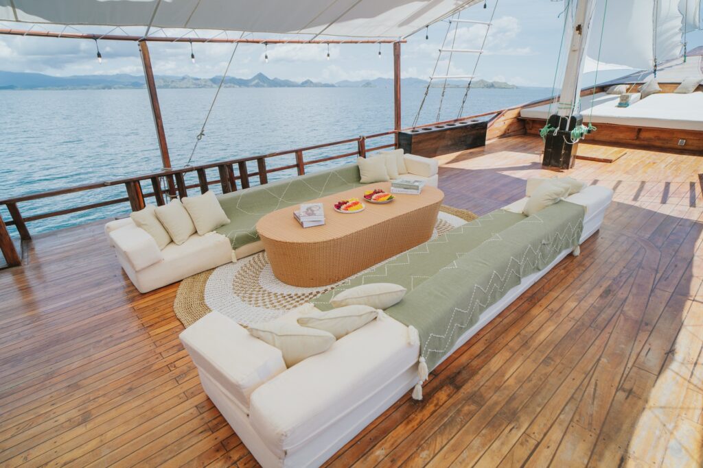 Outdoor lounge deck with tan sofas, sage green runners and a large wood coffee table